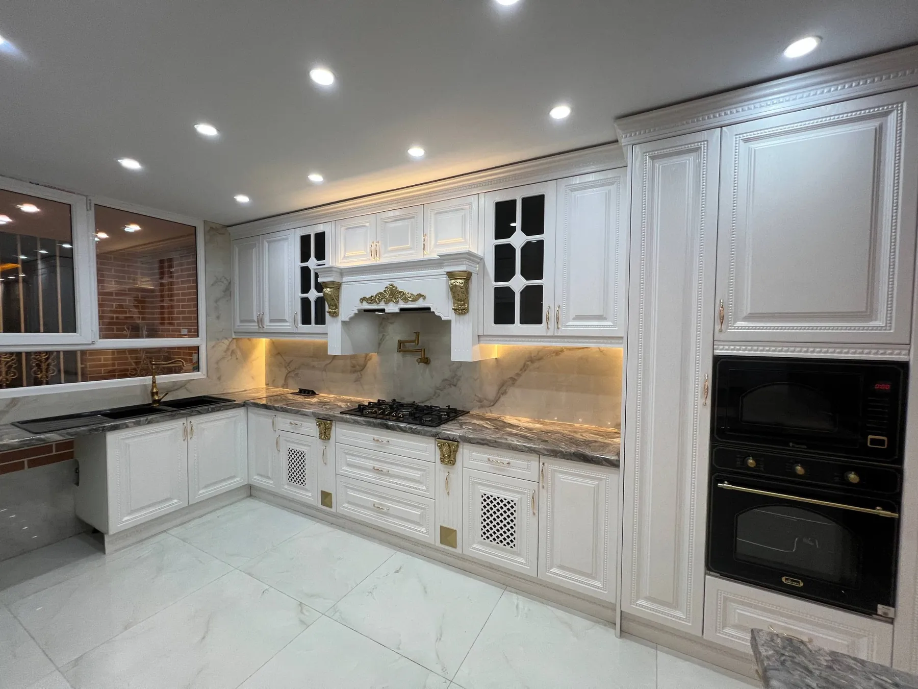 Finished ornate white membrane cabinetry with black glass inserts and gold details