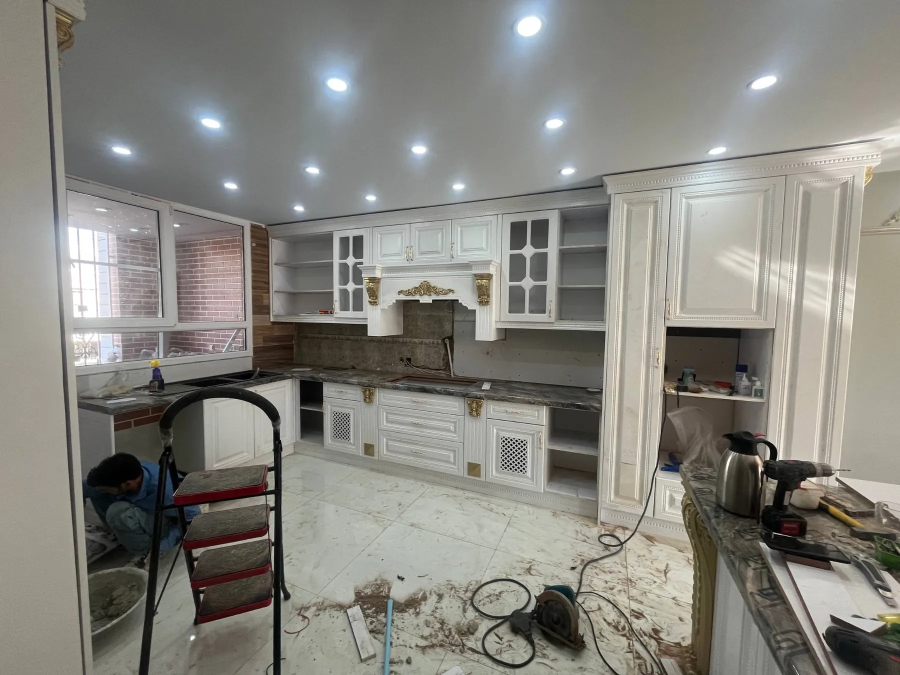 Cabinets and decorative hood surround in progress with tools and unfinished backsplash