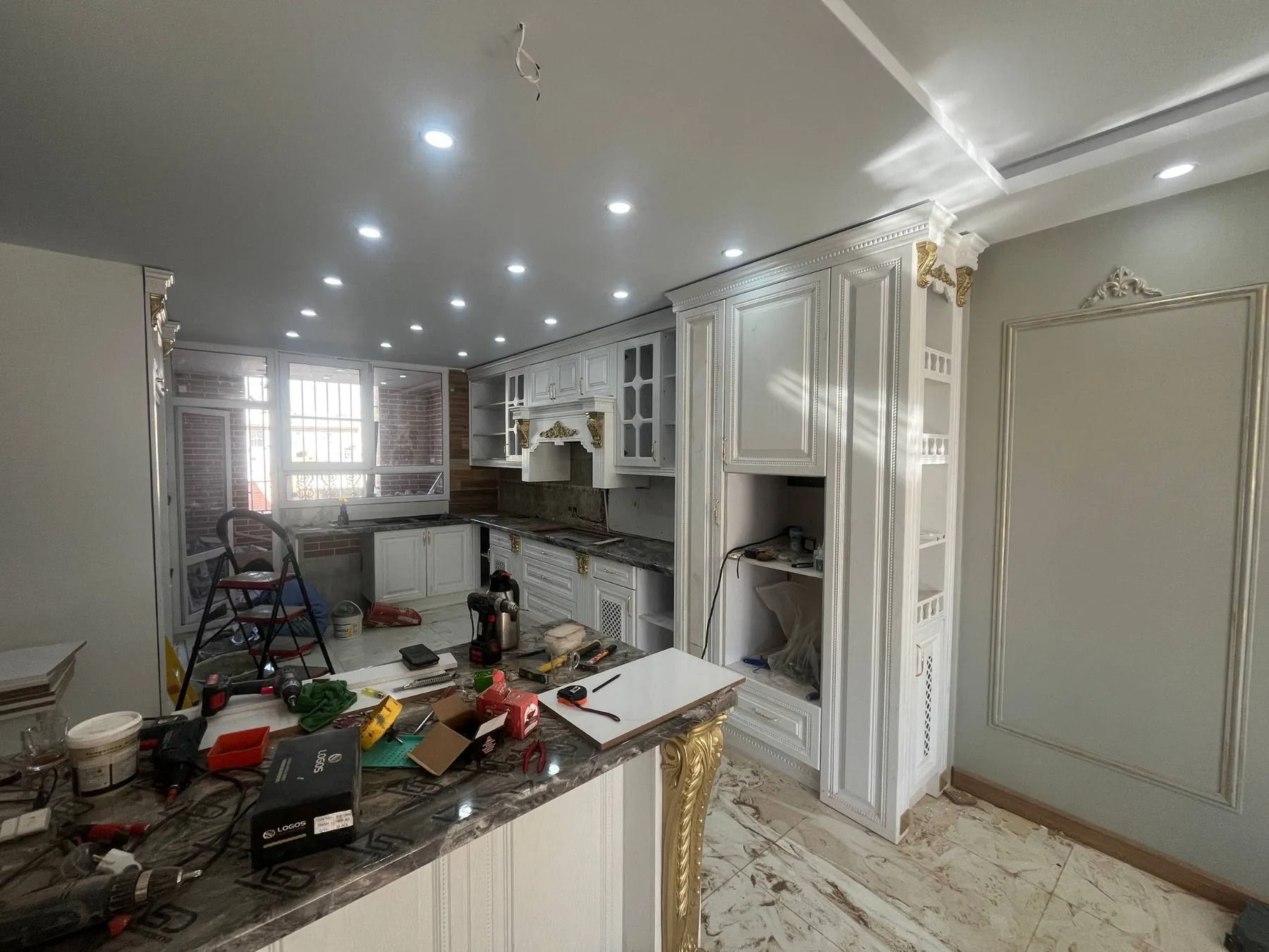 Wide actual work-in-progress scene with tools, kitchen cabinets and peninsula